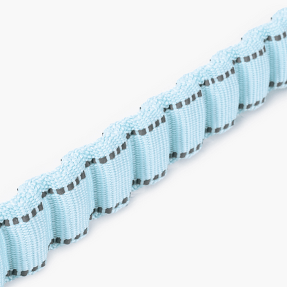 Close-up of a light blue ribbon with black stitching on a white background